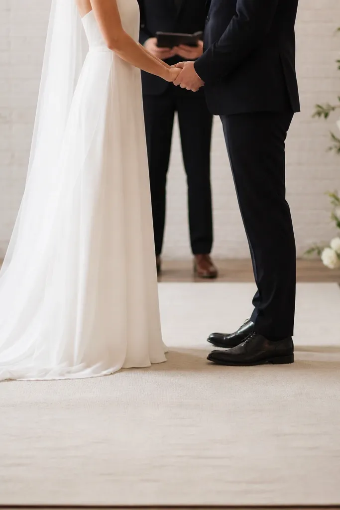 A stage floor runner in matte cream fabric with subtle texture. The runner is low and doesn't rise above the couple's shoes, keeping feet visible.